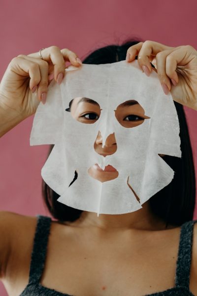 Eine Frau hält sich eine trockene Tuchmaske vor das Gesicht