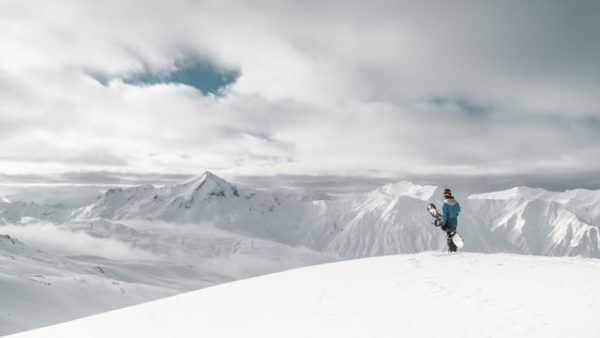 Ein Snowboarder steht am Rand einer beschneiten Klippe