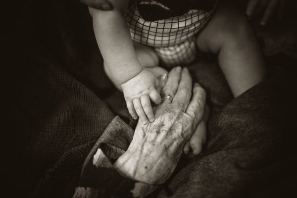 Ein Baby hält die faltige Hand einer älteren Person