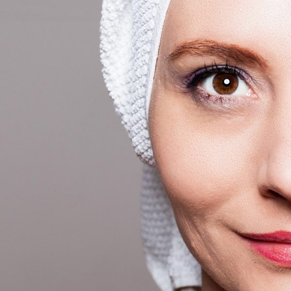 Eine Porträtaufnahme einer Frau mit einem Handtuch auf dem Kopf. Die Hälfte des Gesichts ist abgeschnitten