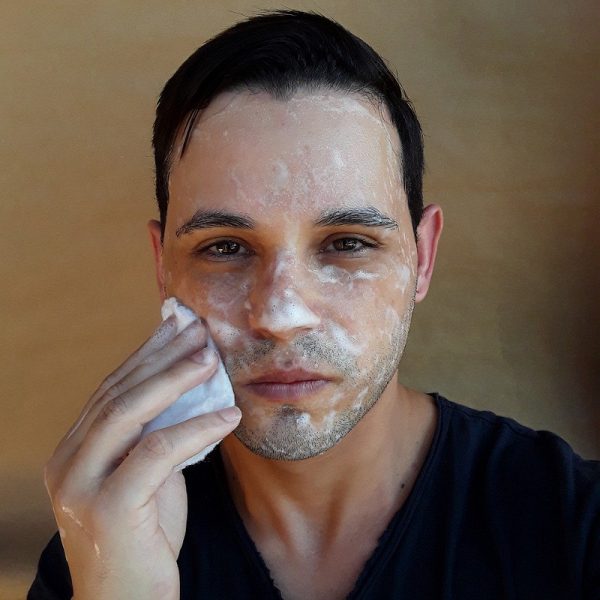 Ein Mann wäscht sich das Gesicht mit einer hellen Seife