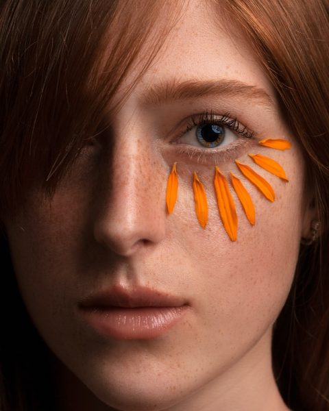 Frau mit Blütenblättern unter den Augen