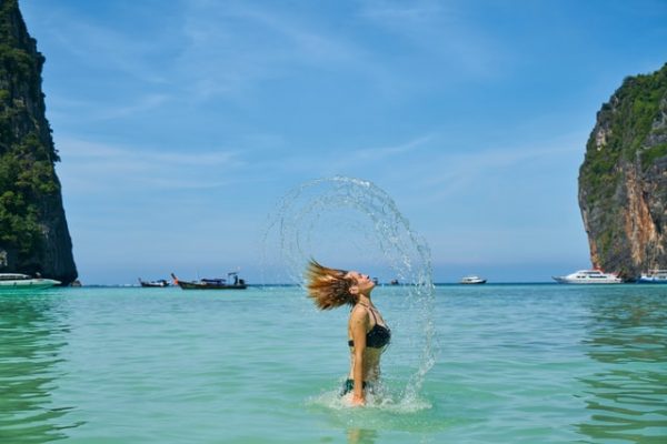 Frau in einer Bucht, die Ihre Haare aus dem Wasser schleudert