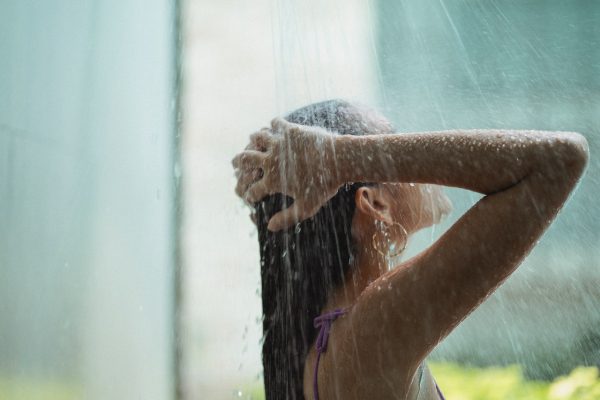 Eine Frau massiert sich unter der Dusche die Kopfhaut