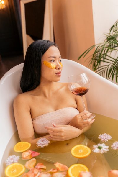 Eine Frau in einer Badewanne mit einem Glas Wein und Augenmasken