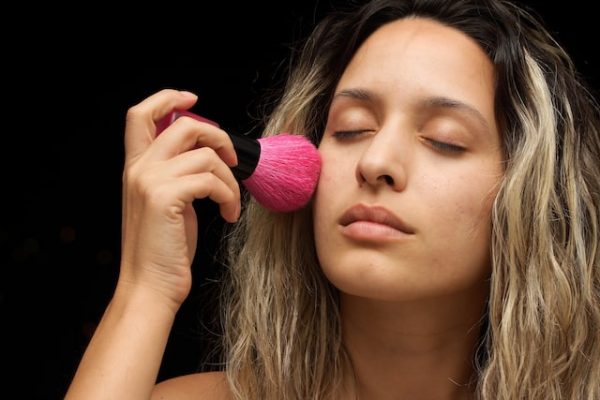 Eine Frau schminkt sich mit pinkem Pinsel