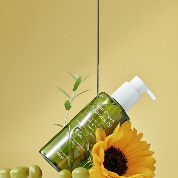 Flüssigkeit fließt auf ein Purito-Produkt, neben dem Oliven und eine Sonnenblume liegen.